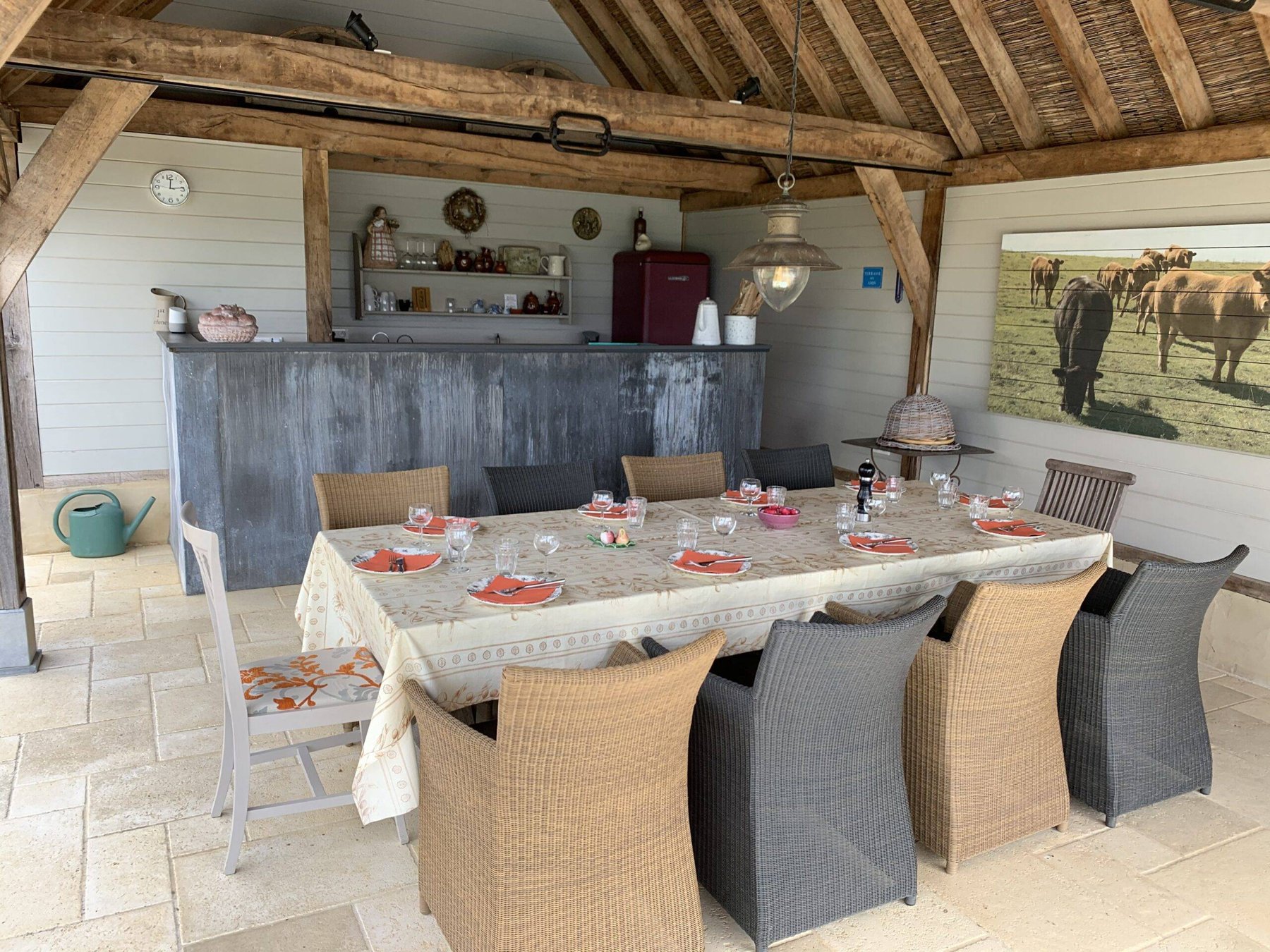 Overdekte buitenkeuken met lange gedekte eettafel bij het zwembad